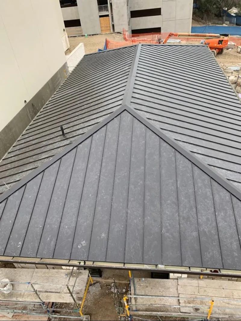 Commercial metal roof construction with crane equipment in Puyallup